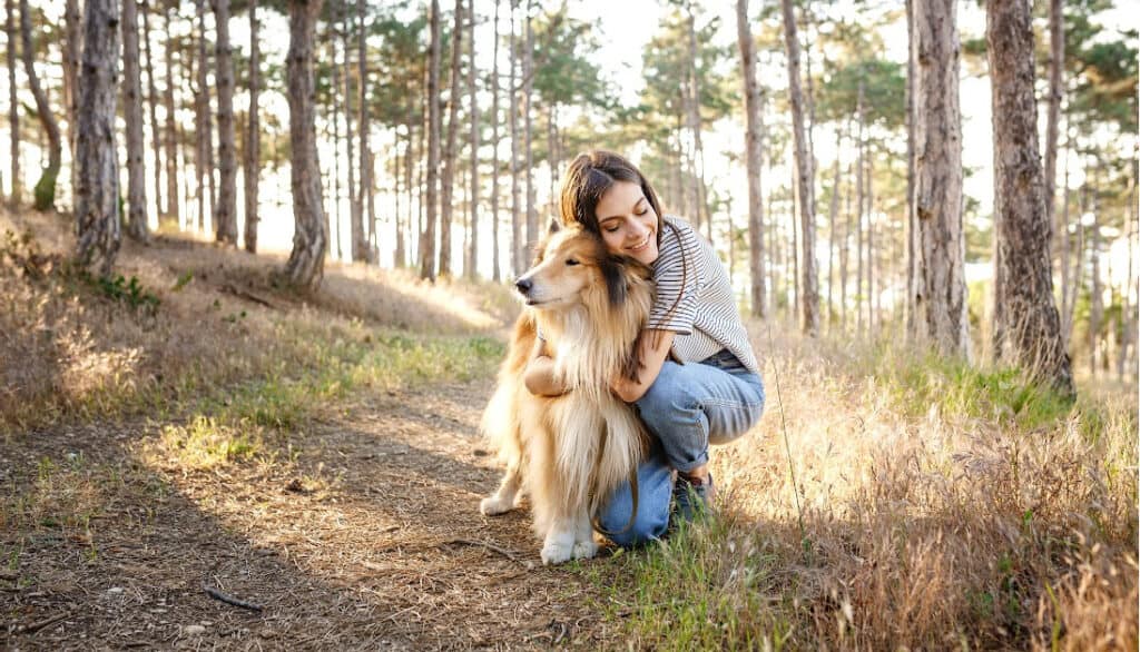 dog being hugged by owner on trail